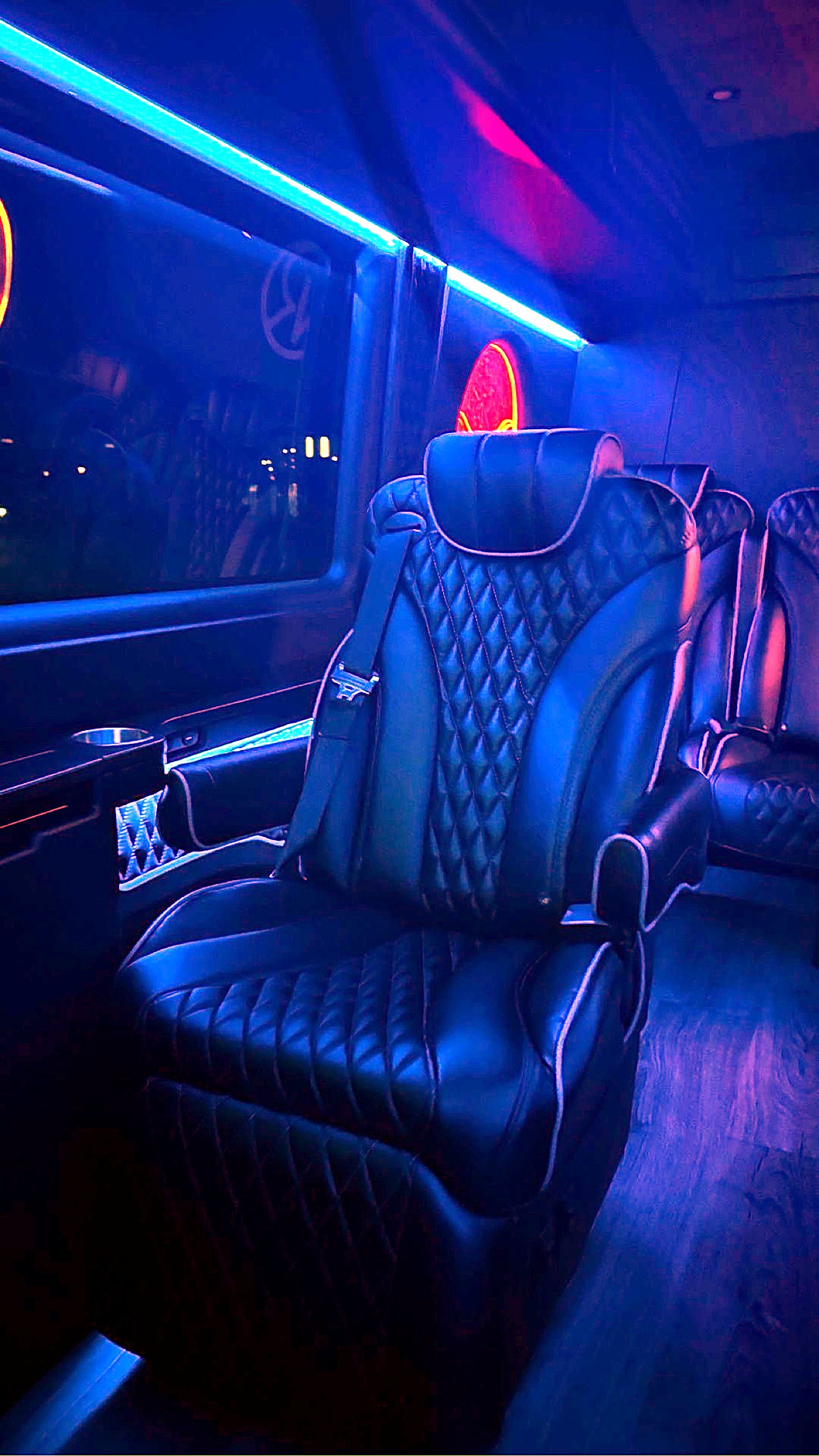 Captain chair beside the window with cupholder console and neon accent lighting