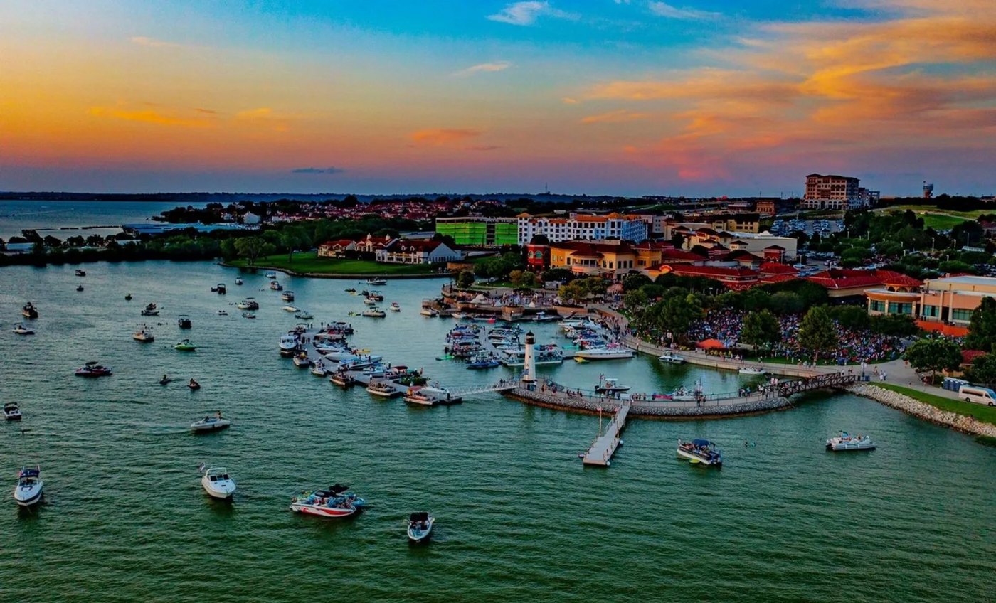 Sunset over Rockwall Harbor on Lake Ray Hubbard, with boats in the marina and the lighthouse on the point